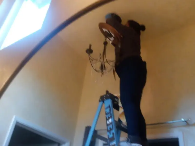 Electrician installing a chandelier in a Raisinville residence